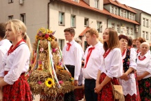 grupa ludzi idąca w korowodzie dożynkowym, ubrana w stroje regionalne