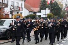 grupa ludzi grający na instrumentach dętych ulicą miasta