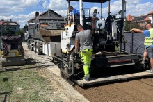 Maszyna nasypująca żwir podczas modernizacji drogi w Stadnikach. Pracownicy ubrani są w odblaskowe stroje