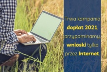 osoba siedząca na łące z komputerem i napis: trwa kampania dopłaty 2021, wnioski tylko przez internet
