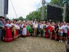 grupa uczestników tańców polskich w strojach regionalnych- czerwonych,niebieskich,zielonych