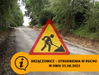 znak roboty drogowe, piniżej napis Brzączowice utrudnienia w ruchu w dniu 23.08.2023 w tle droga w Brzączowicach